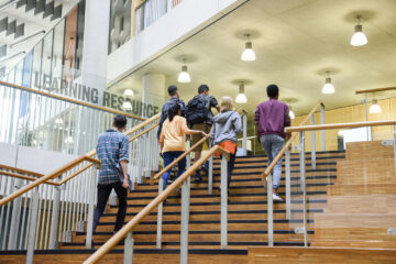 男女大学生穿着便服，走在去上课的路上，上楼梯。